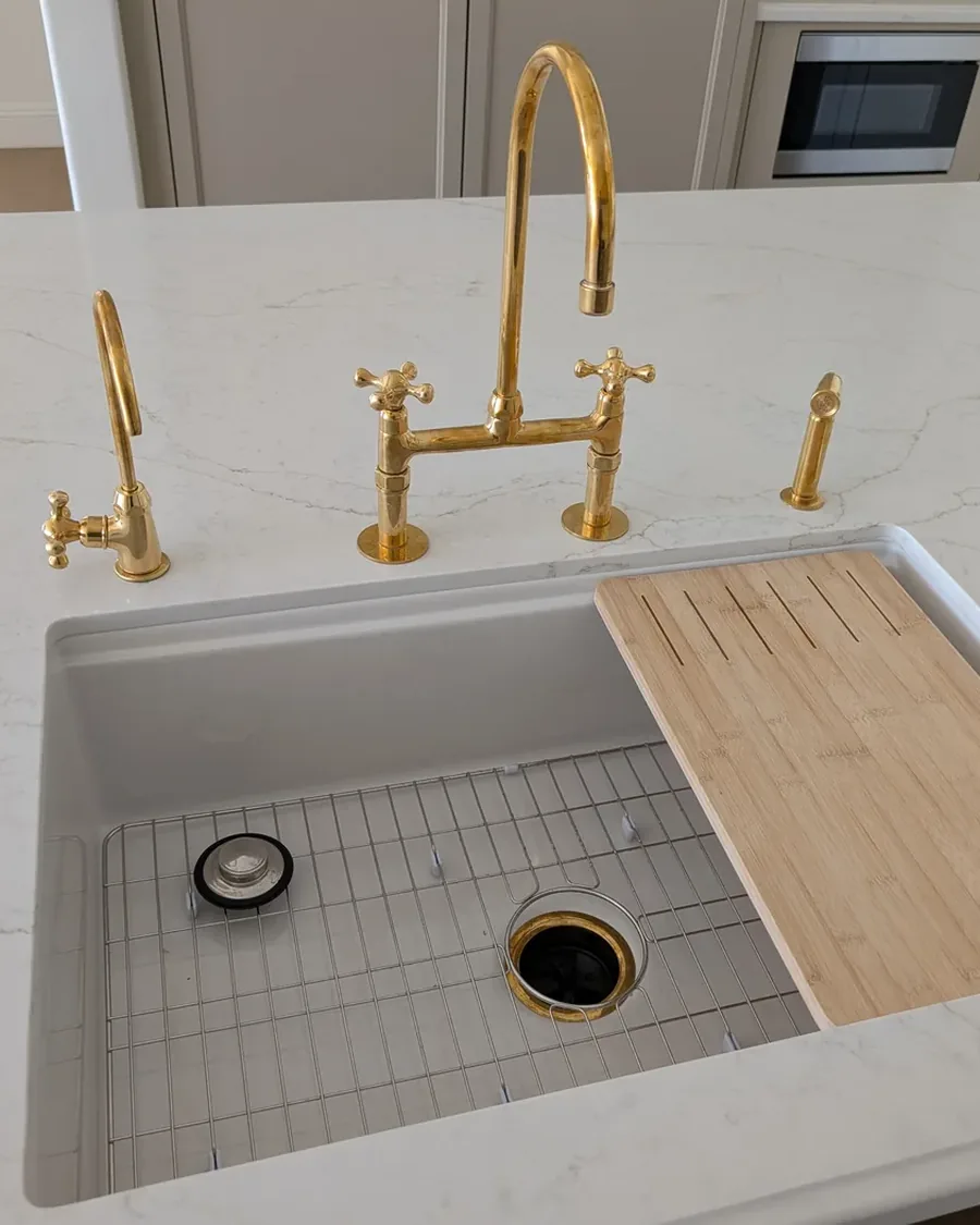 Finished kitchen sink installation by Neil: unlacquered brass bridge faucet, filtered-water tap and undermount sink on a quartz counter in a Prescott home