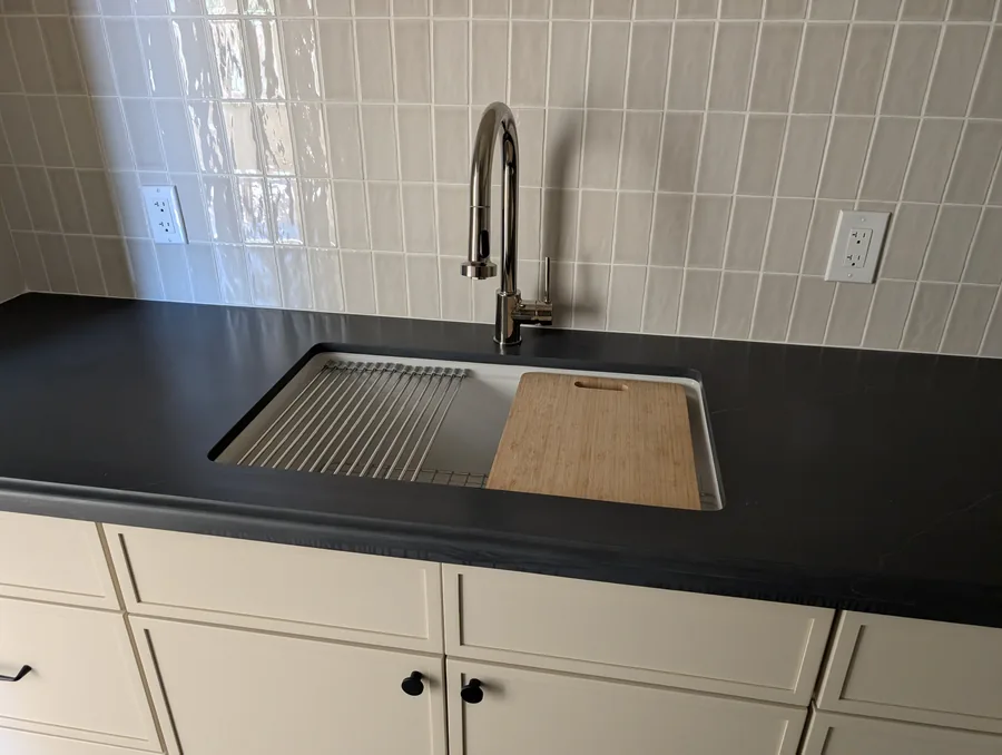 Kitchen sink and pull-down faucet installed in a dark stone countertop