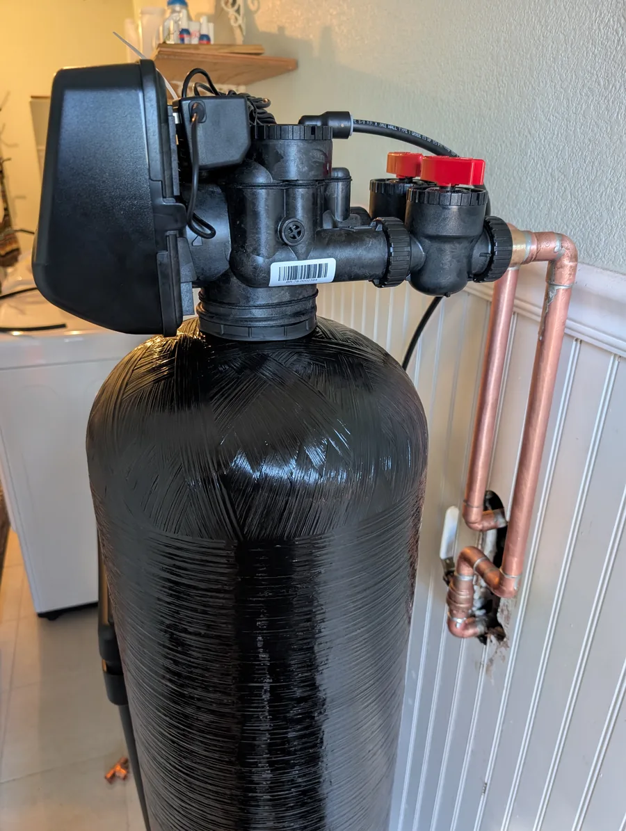 Softener control valve with two red bypass knobs and copper connections
